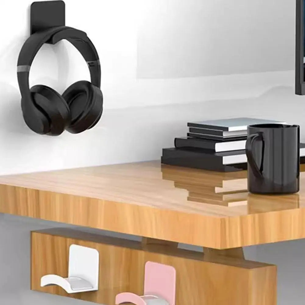 Wooden desk with black headphones hanging, books, and a black mug.